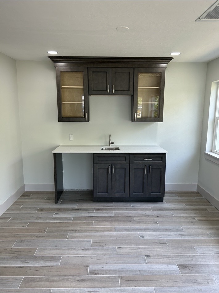 Completed dark wood custom cabinetry with sink and tile flooring